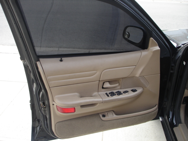 Interior driver's side door panel of a 2001 Ford Crown Victoria, showing tan trim, power window controls, and a side mirror