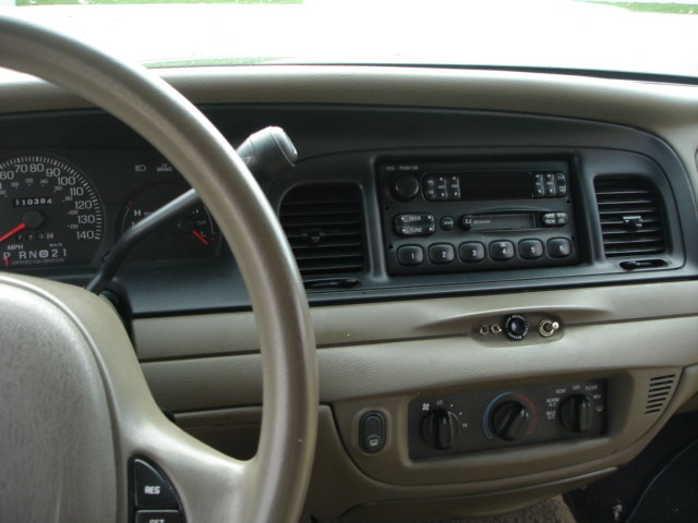 Dashboard interior of a 2001 Ford Crown Victoria, showing the steering wheel, instrument cluster, and radio