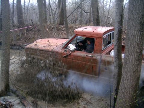 1979 Jeep J-10 - A 1979 Jeep J-10 navigates a muddy off-road course, kicking up a large spray.