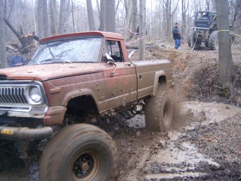 1979 Jeep J-10 - This 1979 Jeep J-10 is shown tackling a challenging muddy trail with another vehicle visible in the background.