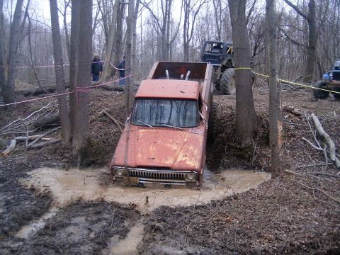 1979 Jeep J-10 - Orange 1979 Jeep J-10 is stuck in a muddy ditch, with another off-road vehicle visible behind it.