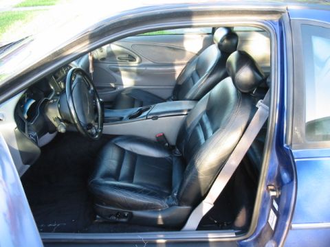 1995 Ford Thunderbird - The interior of a blue car features black leather seats and a dashboard visible through the open door.
