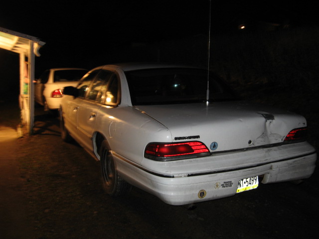 Rear view of a white 1992 Ford Crown Victoria with damage to the trunk lid
