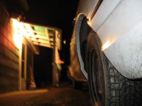 1992 Ford Crown Victoria - Nighttime shot of a car's wheel and fender, with a lit house visible.