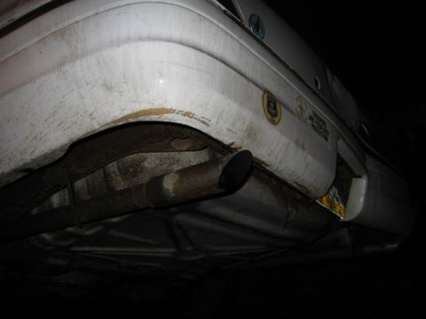 1992 Ford Crown Victoria - Underside view of a white 1992 Ford Crown Victoria, showing the rear bumper and exhaust system.