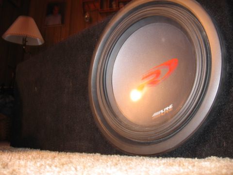 1992 Ford Crown Victoria - Close-up of an Alpine car subwoofer in its enclosure, placed on a carpeted surface.