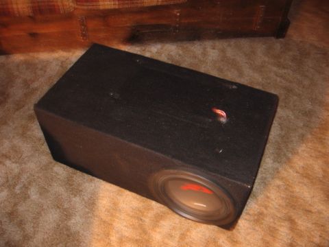 1992 Ford Crown Victoria - A black subwoofer box with a visible speaker cone sits on a carpeted floor.