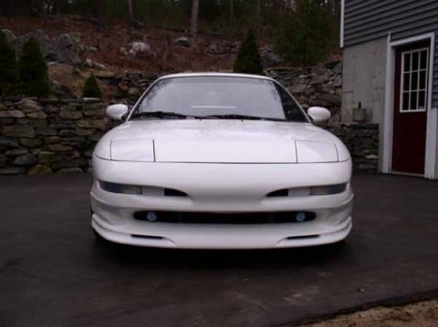 1996 Ford Probe - A white 1996 Ford Probe GT is shown from the front, parked outside a building with a stone wall and trees in the background.
