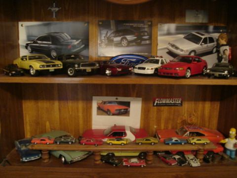 1992 Ford Crown Victoria - A display shelf filled with various model cars and automotive-themed posters.