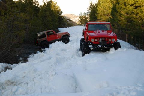 1989 Ford Bronco - A red 1966 Ford Bronco navigates a snowy trail, with another off-road vehicle visible in the background.