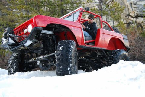 1989 Ford Bronco - Modified 1989 Ford Bronco navigating a snowy terrain with a driver at the wheel.
