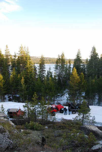 1989 Ford Bronco - Two ATVs and a trailer are parked in a snowy forest clearing next to a lake.