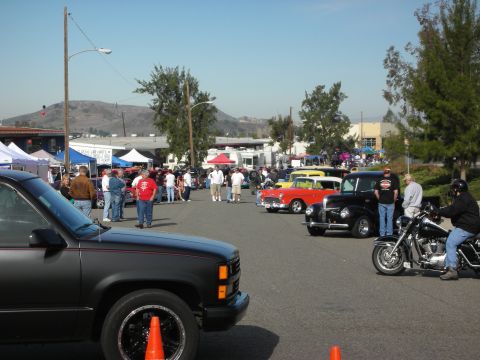 1998 Ford Crown Victoria - A car show event with attendees gathered around various vehicles on a sunny day.
