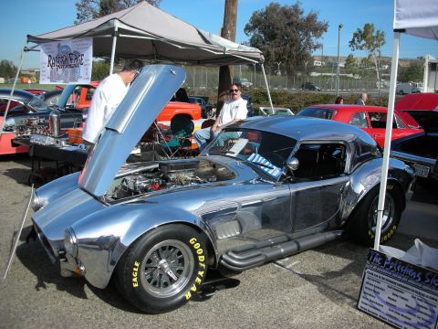 1998 Ford Crown Victoria - A highly polished Shelby Cobra replica is displayed with its hood open, the engine and side pipes.