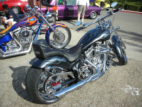 1998 Ford Crown Victoria - Custom choppers with flame graphics are displayed at an outdoor event, with other vehicles in the background.