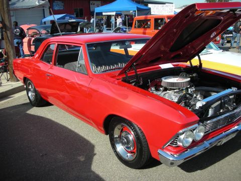 1998 Ford Crown Victoria - A red 1966 Chevrolet Chevelle coupe is displayed with its hood open, showing the engine and chrome details.