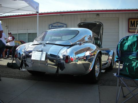1998 Ford Crown Victoria - Chrome sports car with racing stripes and a license plate is parked outside a building.