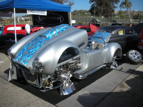 1998 Ford Crown Victoria - A silver custom car with blue flame graphics is displayed with its hood and engine exposed.