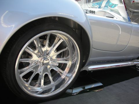 1998 Ford Crown Victoria - A silver sports car is shown from the side, highlighting its chrome multi-spoke wheels and side exhaust pipe.
