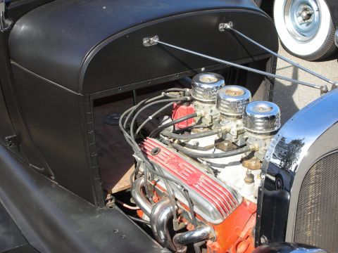 1998 Ford Crown Victoria - A close-up view of a modified V8 engine, a triple carburetor setup and custom valve covers.
