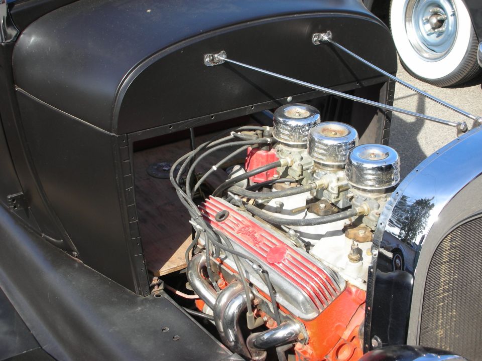 Chrome-topped V8 engine with orange block and white valve covers in a black hot rod