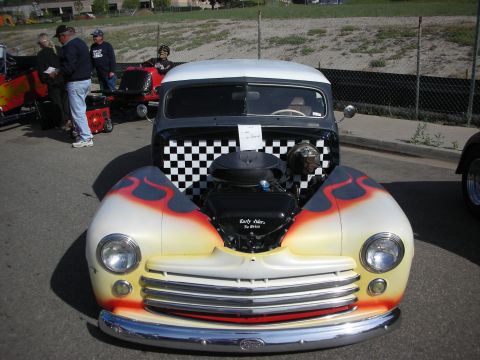 1998 Ford Crown Victoria - Custom hot rod pickup truck with flame paint and checkerboard grille on display.