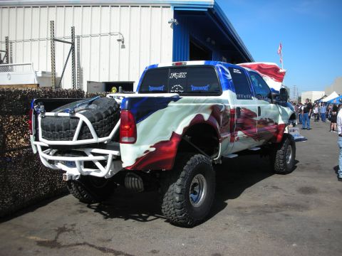 1998 Ford Crown Victoria - A custom Ford truck with a patriotic paint job and off-road modifications is parked outside.