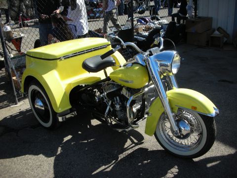 1998 Ford Crown Victoria - A bright yellow trike motorcycle is parked outdoors, a distinctive rear storage unit and chrome accents.