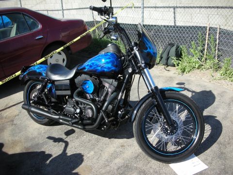 1998 Ford Crown Victoria - A custom motorcycle with a striking blue flame paint job is parked outdoors, with a caution tape barrier and a car in the background.