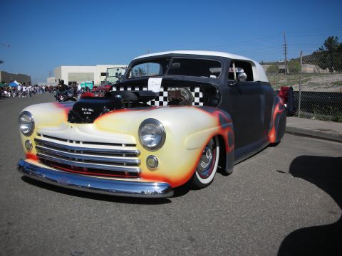 1998 Ford Crown Victoria - Customized hot rod with flame paint and checkerboard engine cover is parked outdoors.