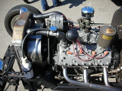 1998 Ford Crown Victoria - Close-up of a Ford flathead V8 engine, likely from the 1940s, with visible spark plug wires and exhaust manifolds.