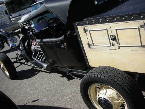 1998 Ford Crown Victoria - A custom hot rod with a black body and a light-colored wooden bed is parked on a street.