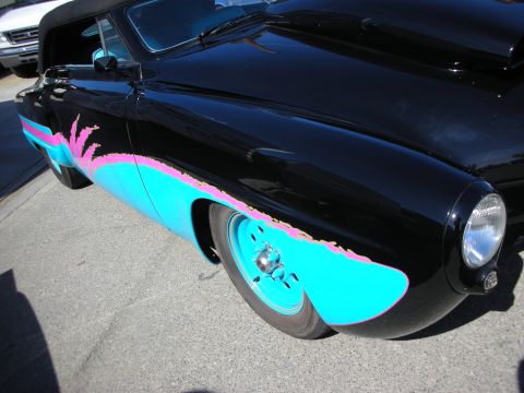 1998 Ford Crown Victoria - A black custom hot rod with vibrant graphics is parked next to a white truck.
