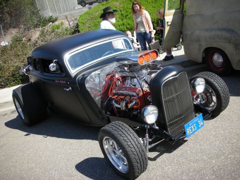 1998 Ford Crown Victoria - A custom black hot rod with a powerful V8 engine is displayed at a show, a prominent chrome intake and a California license plate.