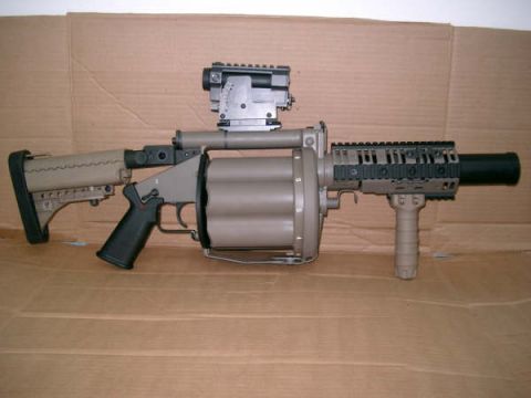 1998 Ford Crown Victoria - A tan and grey grenade launcher is shown with a scope mounted on top and a vertical foregrip attached to the front.