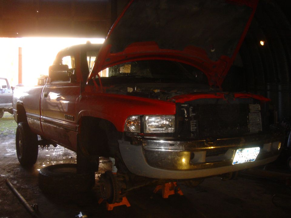 Red pickup truck with hood open, on jack stands, in a garage