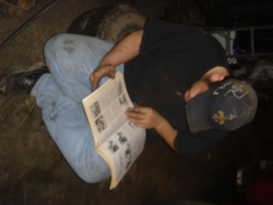 Man in blue jeans and black t-shirt reads a manual open to pages with diagrams