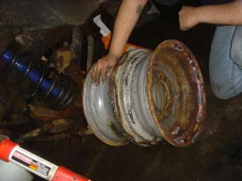 1979 Ford F-250 - Hands hold two rusty wheels and a blue shock absorber, suggesting shop work on a vehicle.