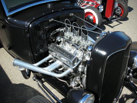 1998 Ford Crown Victoria - Hot rod engine detail with multiple carburetors and exhaust headers, another car in background.