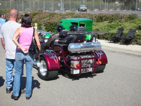 1998 Ford Crown Victoria - A custom trike motorcycle with a large silver fuel tank and two passengers is parked outdoors.