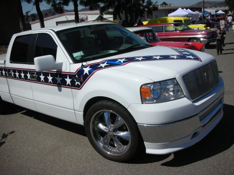 1998 Ford Crown Victoria - A white pickup truck is parked at an outdoor event with other vehicles visible.