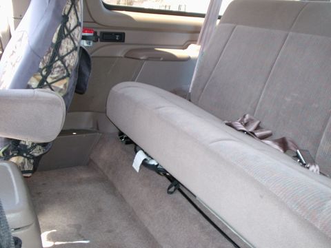 1996 Ford Bronco - Tan cloth rear bench seat in a Ford truck cab, with a camouflage front seat back and cargo net visible.