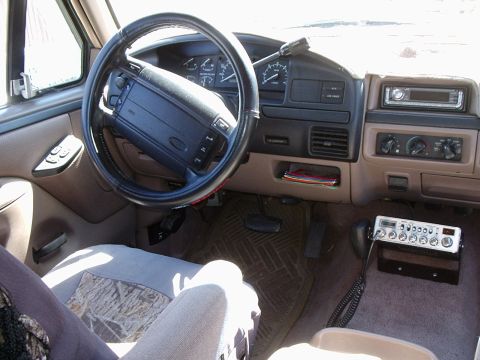 1996 Ford Bronco - Interior view of a Ford truck/SUV from the driver's side, showing a black steering wheel with Ford emblem, tan/beige dashboard and gauge cl…