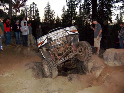 1995 Ford Bronco - This heavily modified SUV is navigating a difficult rocky trail with onlookers observing the action.