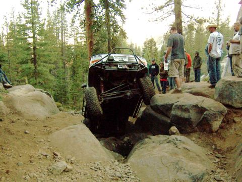 1995 Ford Bronco - An off-road vehicle tackles a challenging rocky obstacle with spectators watching.