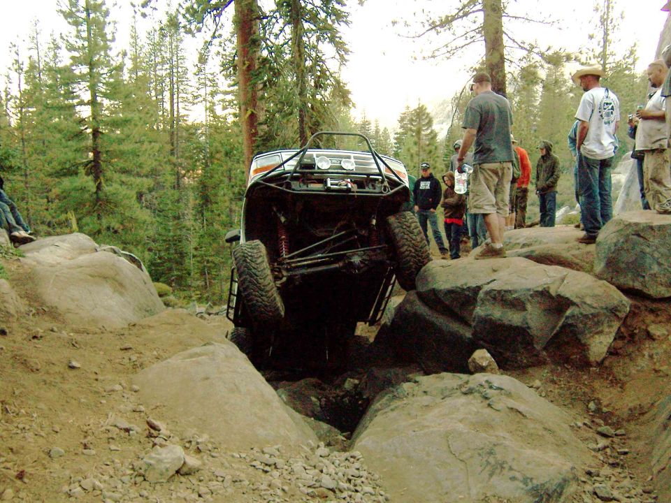 Off-road vehicle with modified roll cage and suspension navigating a rocky terrain
