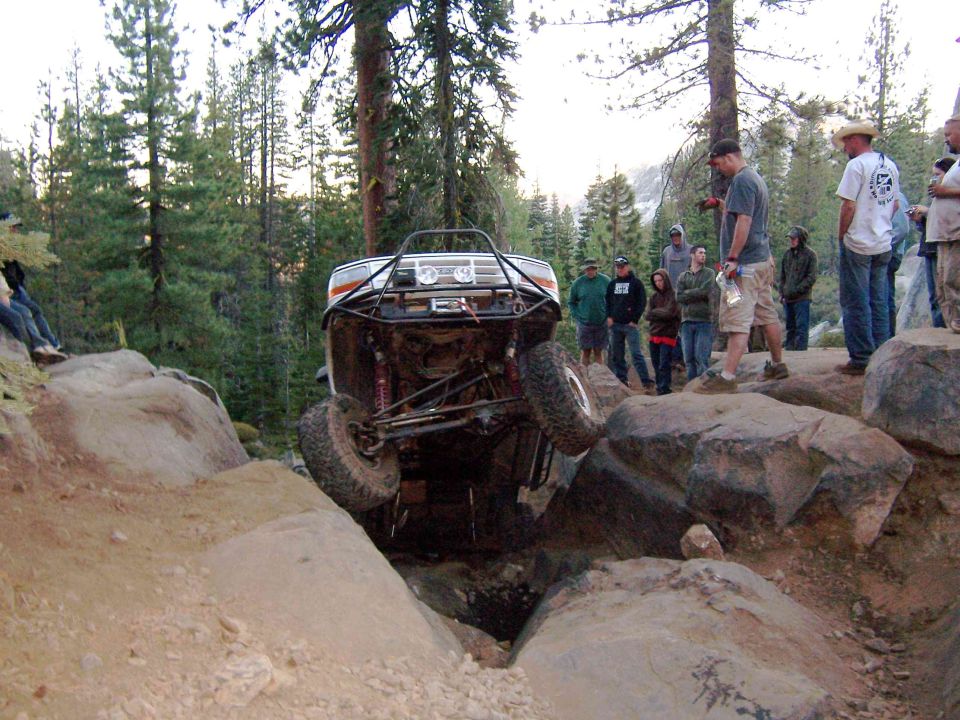 1995 Ford Bronco modified for off-roading, tilted on rocks with front wheel off the ground