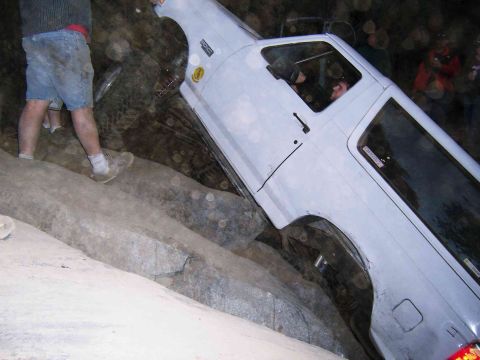 1995 Ford Bronco - A white Ford Bronco navigates a rocky terrain, with a person visible in the driver's seat.