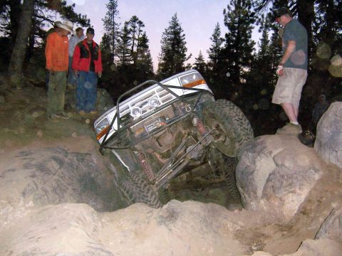 1995 Ford Bronco - Modified white SUV tackles a challenging rocky obstacle course.