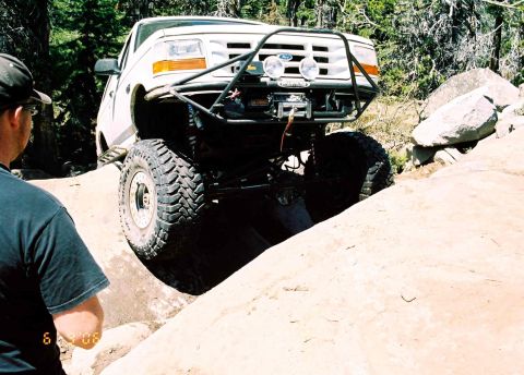 1995 Ford Bronco - This modified Ford truck is navigating a challenging rocky terrain, with a person observing the action.